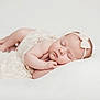 baby, newborn, sleeping, headband, bow, lace, dress, blanket, white_background, soft_light, portrait, studio_photography, infant, peaceful, hands, feet, chubby_cheeks, pillow, lying_down, cute
