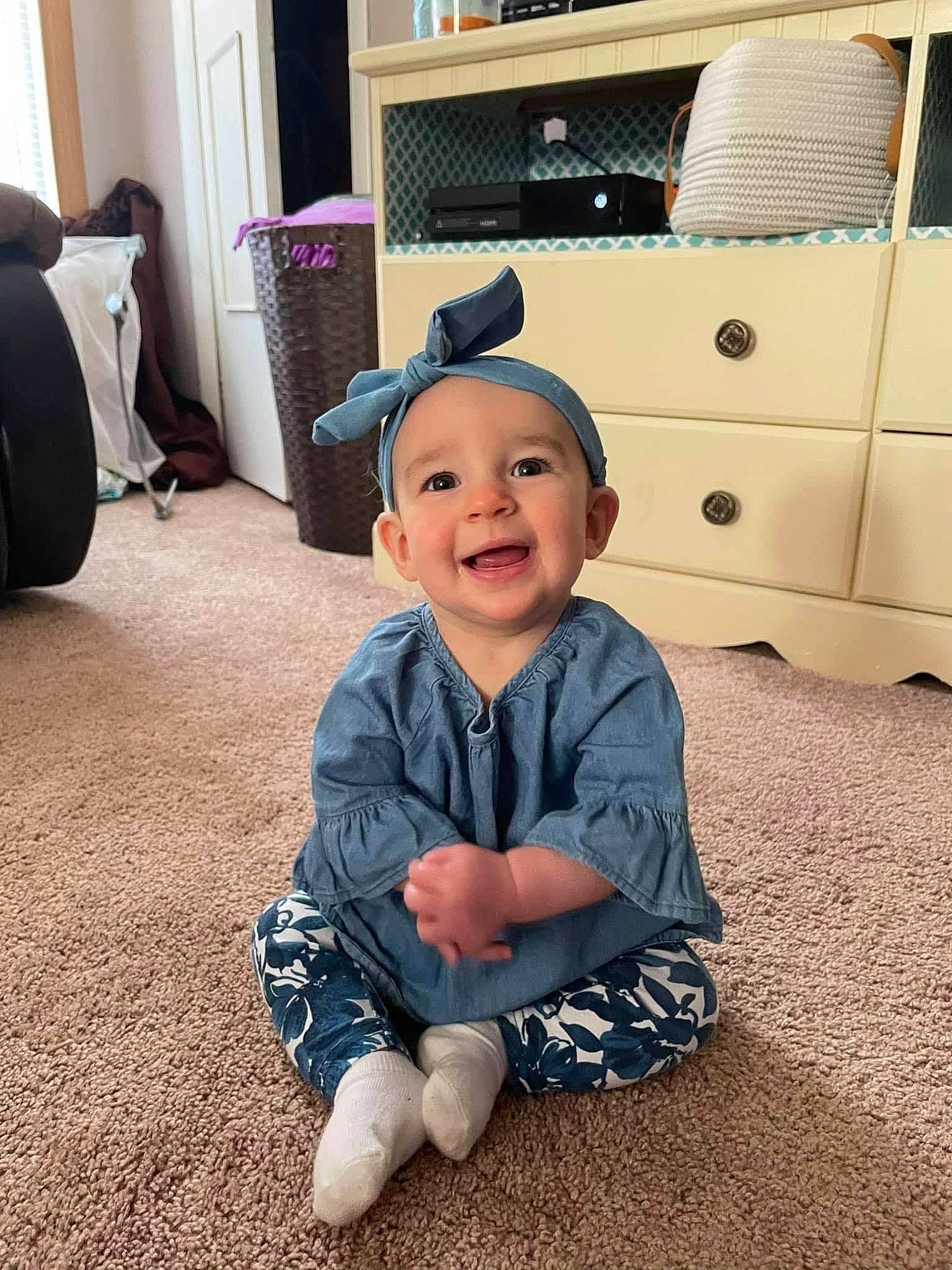 Aria Grace is registered to the contest to win money with this photo: baby, baby_toddler_clothing, cabinetry, chest_of_drawers, child, comfort, drawer, floor, flooring, happy, hat, home_appliance, joy, living_room, person, room, shoe, sleeve, smile, sneakers