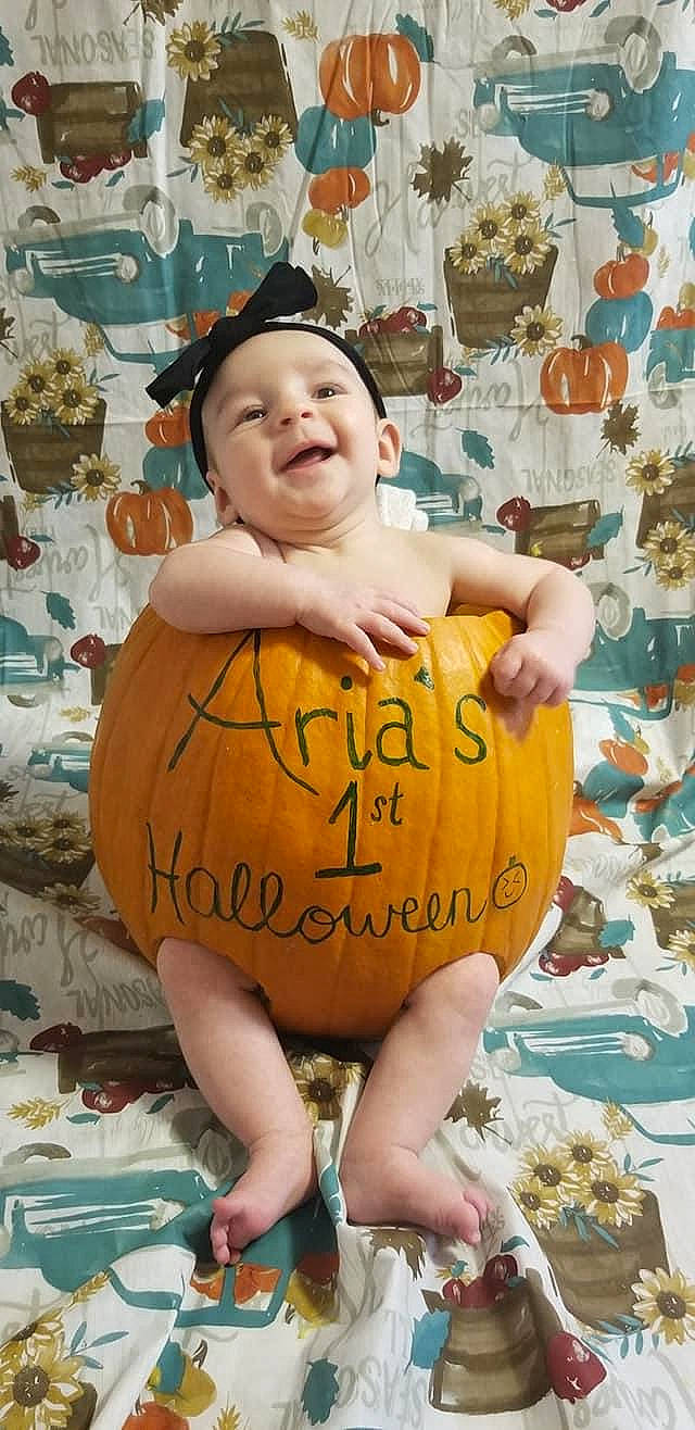 Aria Grace is registered to the contest to win money with this photo: baby, calabaza, child, fun, handwriting, happy, headwear, human, joy, leisure, orange, person, photo_caption, pumpkin, room, shorts, sitting, smile, summer, toddler