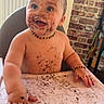 baby, high_chair, chocolate, messy, smiling, happy, face, hands, table, food, indoor, child, cute, playful, dirt, skin, necklace, expression, toddler, mess