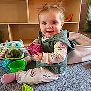 Daphne joined the competition — help win amazing prizes! baby, child, toy, carpet, indoor, smile, cute, play, colorful, block, green, purple, pink, clothing, vest, socks, face, person, happy, floor