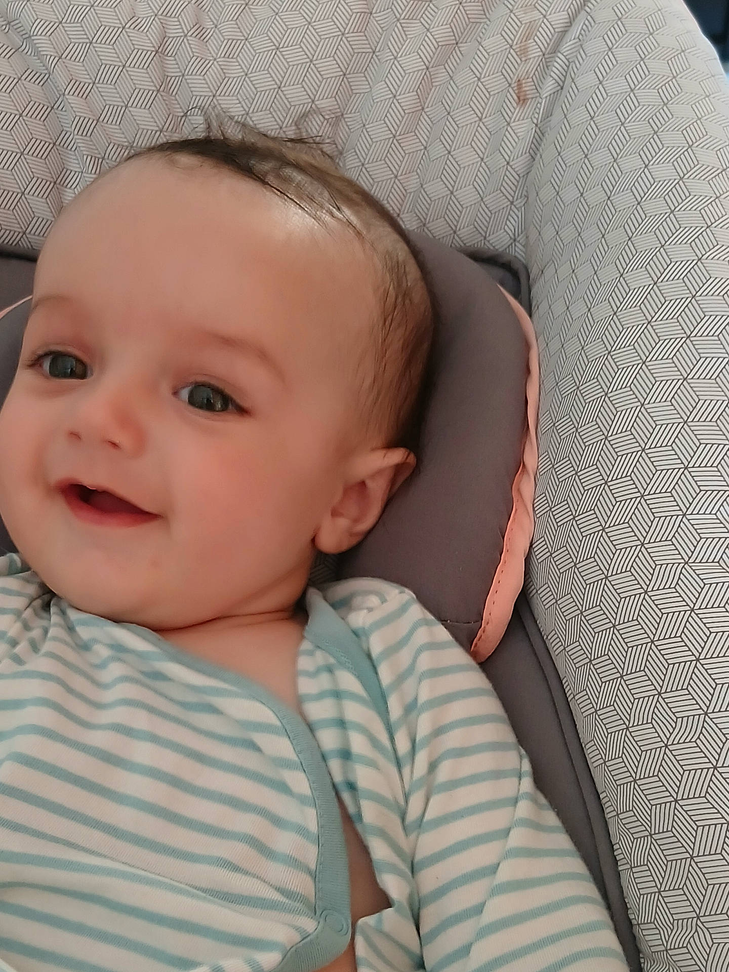 Mathys participe au concours pour gagner de l'argent avec cette photo : baby, baby_clothes, child, closeup, cushion, cute, face, happy, head, indoors, infant, patterned_background, person, portrait, relaxing, skin, smiling, soft_lighting, striped_clothing, young_child
