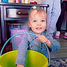 Journee is registered to the contest to win money with this photo: child, toddler, bucket, indoor, table, soda_can, flower_vase, carpet, floor, jeans, jacket, toy, person, hand, smile, face, blue_eyes, purple_flower, plastic_bucket, casual_clothing