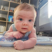 Charlie joined the competition — help win amazing prizes! baby, infant, tummy_time, carpet, curious, blue_eyes, indoor, furniture, bookshelf, toy, child, person, face, skin, hair, cute, portrait, expression, home, floor