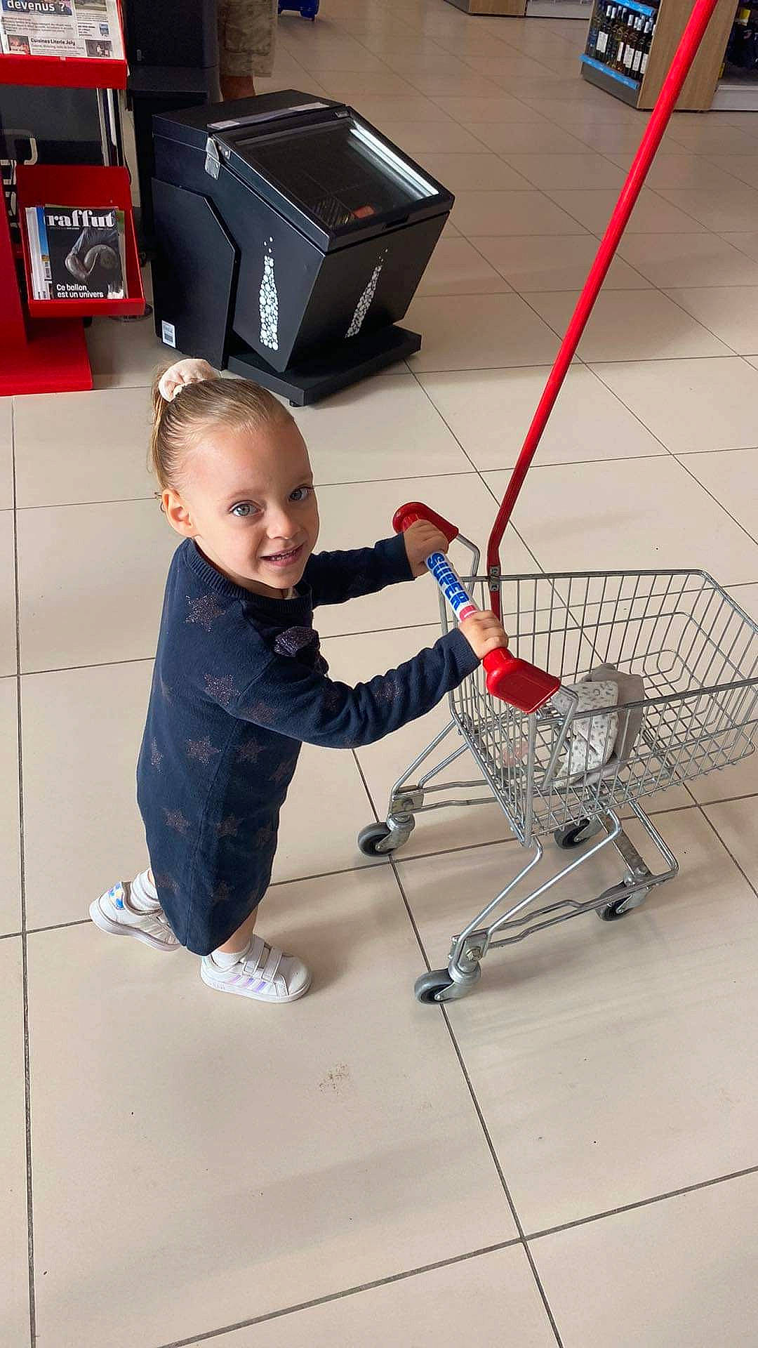 Lyna participe au concours pour gagner de l'argent avec cette photo : box, cart, child, cleanliness, engineering, floor, flooring, fun, human_leg, joy, leg, machine, person, retail, service, shipping_box, shopping_cart, smile, tire, toddler