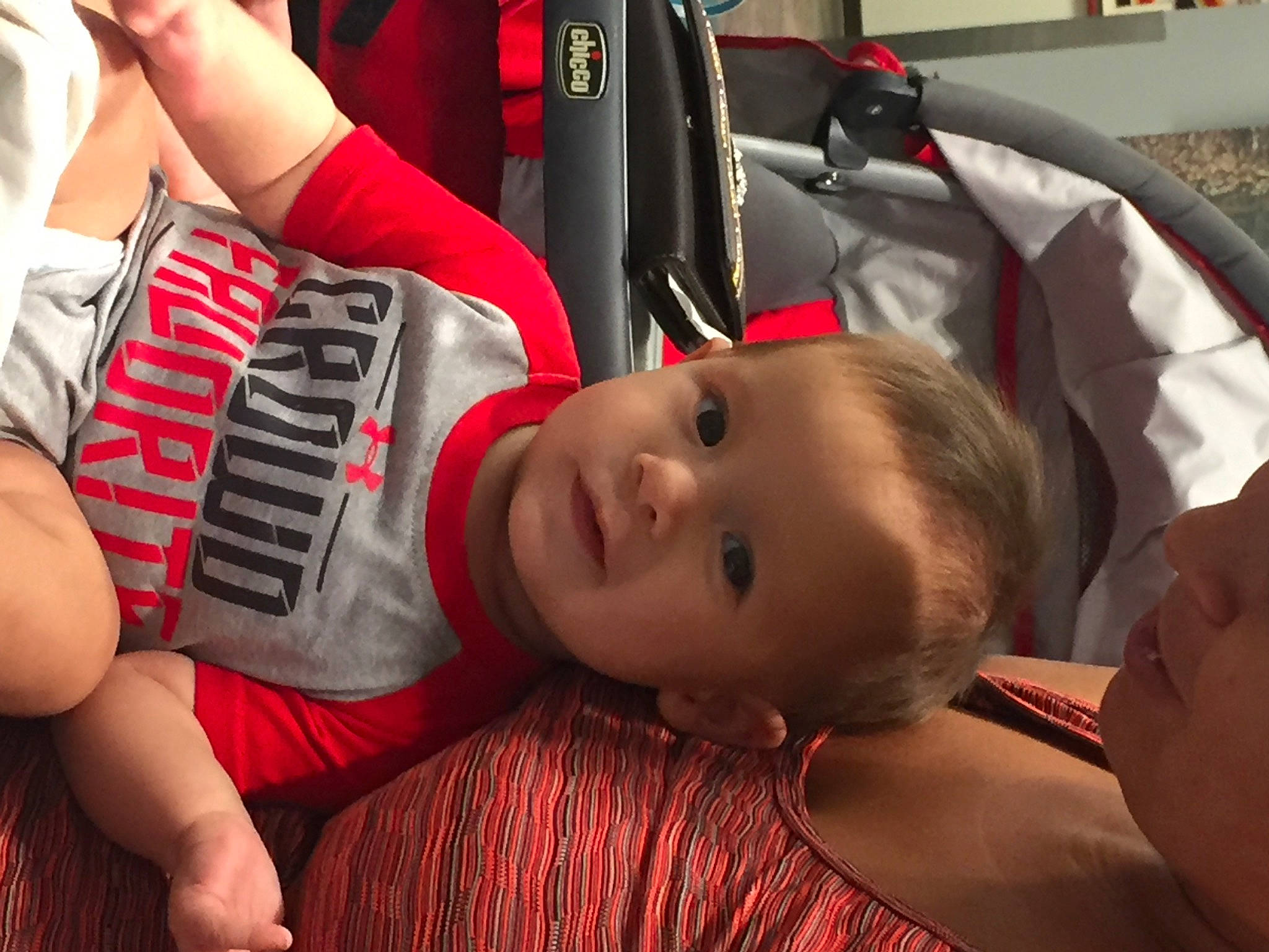 Silas is registered to the contest to win money with this photo: baby, baby_carriage, baby_products, bag, carmine, child, comfort, facial_expression, fashion_accessory, fun, happy, human_leg, joint, knee, leisure, luggage_and_bags, person, red, sitting, thigh