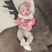 Manel a rejoint le concours — aidez-le/la à gagner de superbes lots ! baby, bib, bow, bunny_slippers, child, couch, cozy, eyes, floral_print, hands, headband, indoor, infant, living_room, pants, pillow, portrait, slippers, smile, sofa