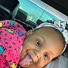baby, child, infant, face, smiling, tongue_out, portrait, car, vehicle, blanket, pink_blanket, bow, headband, sitting, lying_down, indoor, daylight, window, playful, selfie