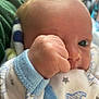 baby, newborn, infant, hand, fist, face, eye, onesie, pajamas, star_pattern, blue_trim, blanket, soft_skin, close_up, portrait, cradled, eyelash, cheek, indoors, cute