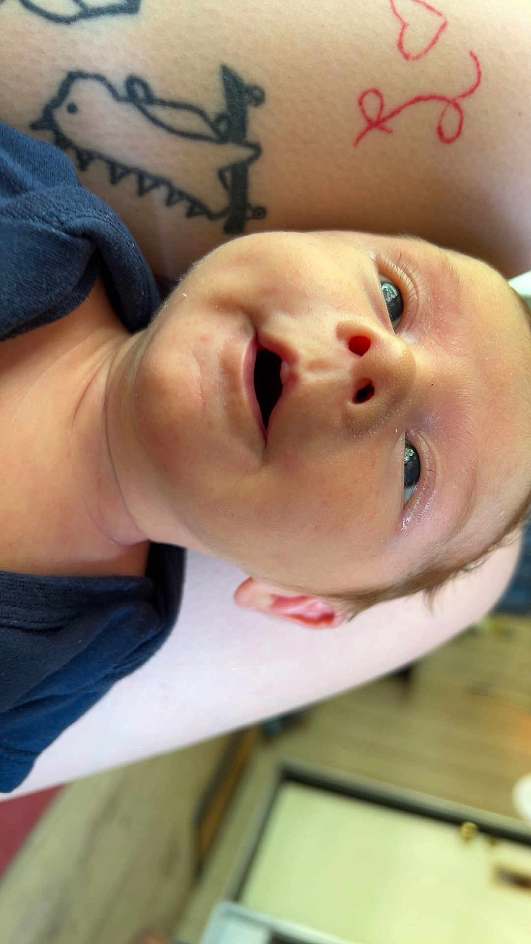 Weston is registered to the contest to win money with this photo: baby, newborn, smiling, face, tattoo, arm, skin, indoor, closeup, child, infant, person, expression, cute, eyes, happy, human, people, portrait, love