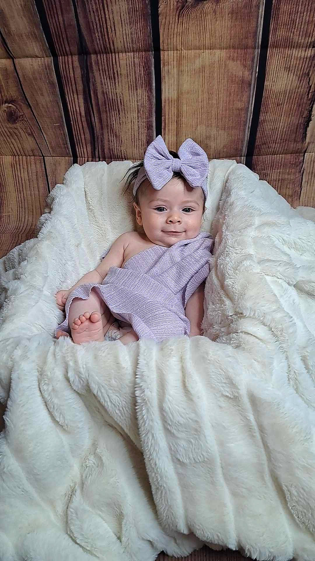 Arya joined the competition — help win amazing prizes! baby, baby_toddler_clothing, bedding, bridal_accessory, child, comfort, dress, event, eye, face, happy, headwear, linens, mammal, person, room, sitting, skin, sleeve, smile