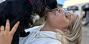 Artémis a rejoint le concours — aidez-le/la à gagner de superbes lots ! affection, black_dog, blonde_hair, candid, close_up, daylight, dog, face, flags, friendly, glasses, holding, love, nose_to_nose, outdoor, person, pet, portrait, sky, white_hoodie