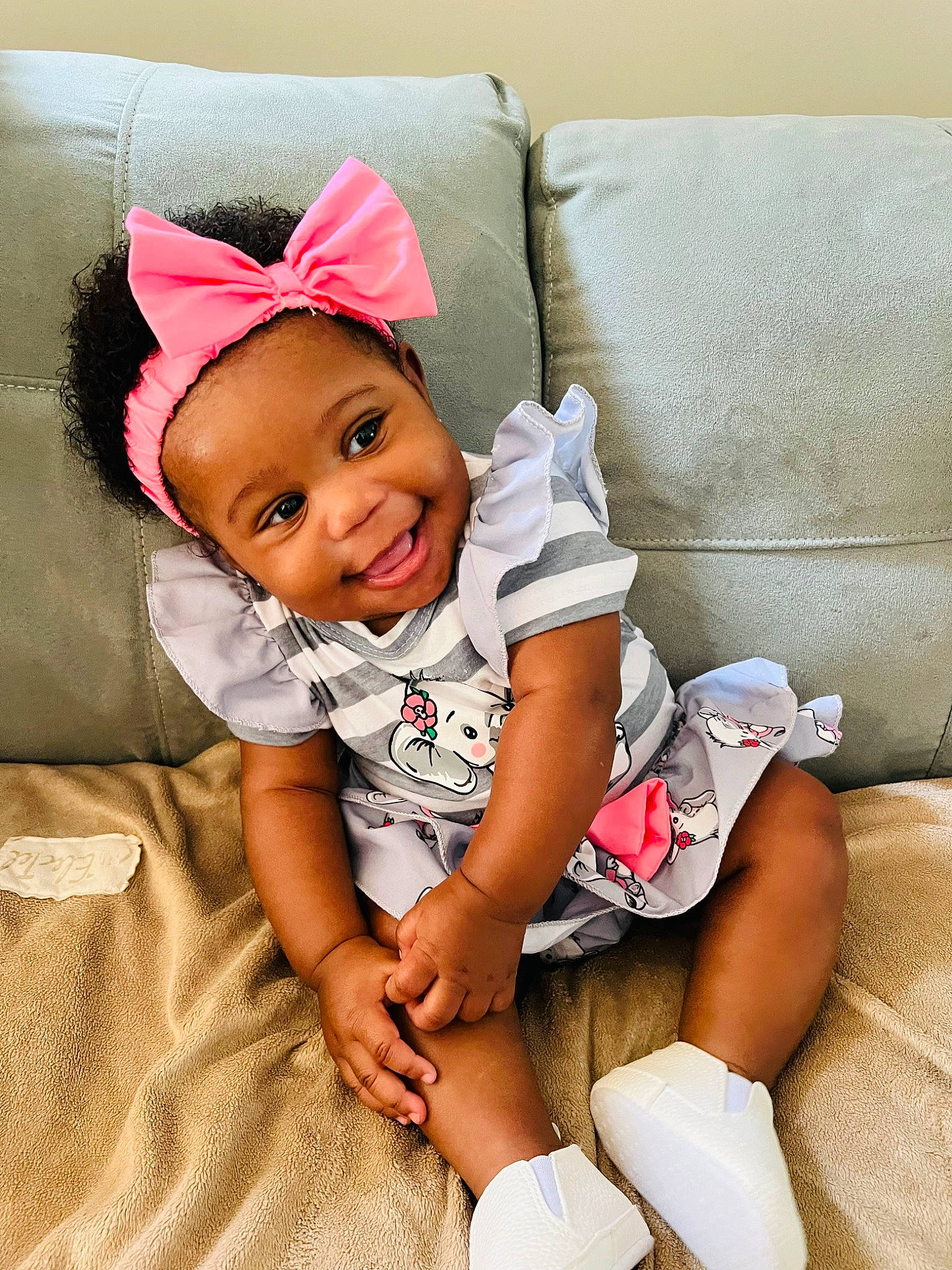Kori is registered to the contest to win money with this photo: baby, baby_toddler_clothing, cap, child, comfort, couch, face, happy, hat, human_leg, joy, knee, pattern, person, pink, shorts, sitting, sleeve, smile, sock