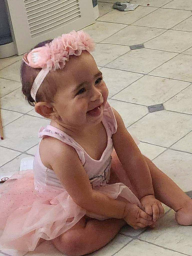 Dezirae joined the competition — help win amazing prizes! baby, baby_laughing, baby_toddler_clothing, dress, face, fashion_accessory, flooring, foot, fun, happy, head, headband, headgear, headpiece, human_leg, person, pink, skin, smile, thigh