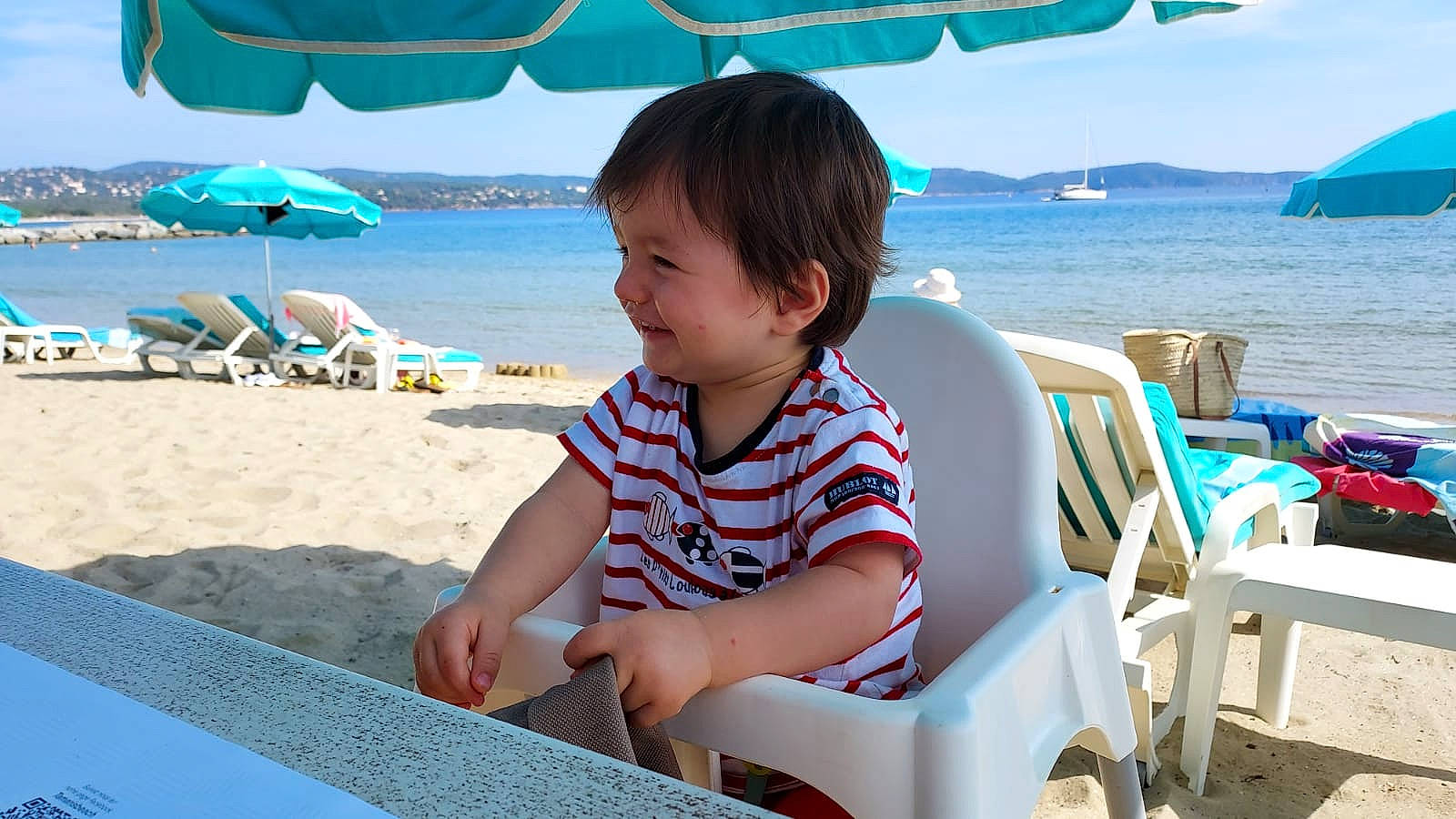 Diego participe au concours pour gagner de l'argent avec cette photo : azure, beach, beauty, blue, chair, comfort, fun, holiday, leisure, outdoor_furniture, people_on_beach, person, shade, sky, smile, summer, sunlounger, toddler, travel, umbrella