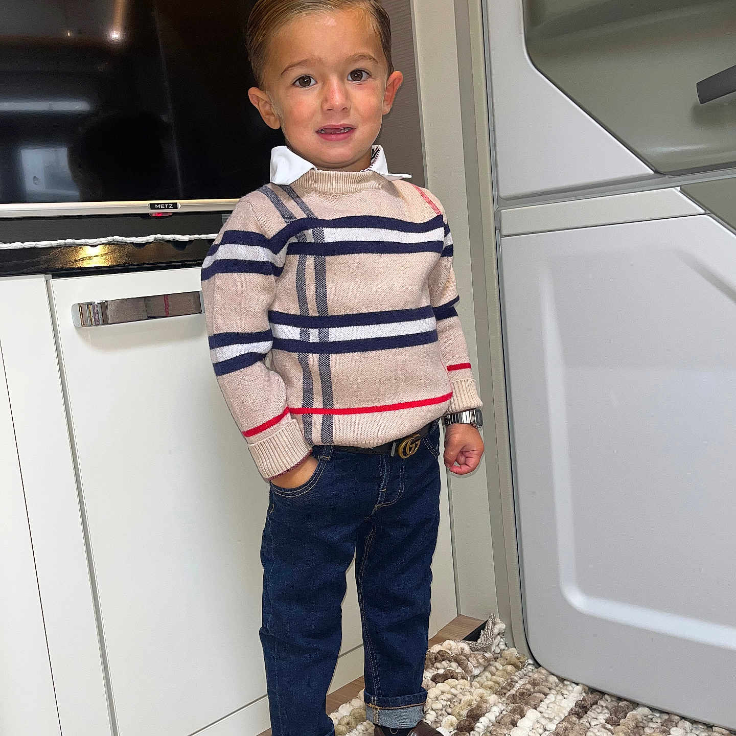 Peter participe au concours pour gagner de l'argent avec cette photo : blue_jeans, boy, brown_shoes, cabinet, carpet, child, confident, cute, fashionable, hair_slicked_back, hand_in_pocket, indoor, modern_interior, portrait, smiling, standing, striped_sweater, television, watch, young
