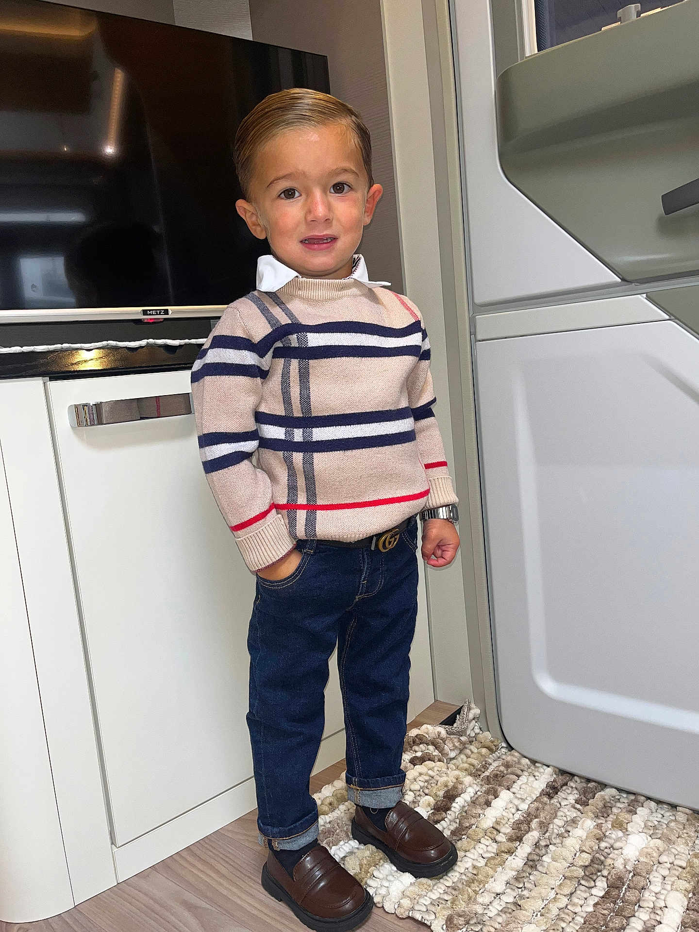 Peter participe au concours pour gagner de l'argent avec cette photo : child, boy, portrait, indoor, striped_sweater, blue_jeans, brown_shoes, watch, hand_in_pocket, carpet, cabinet, television, modern_interior, standing, confident, smiling, hair_slicked_back, fashionable, young, cute