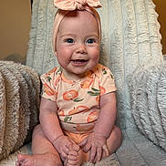 Adeline joined the competition — help win amazing prizes! baby, child, smiling, blue_eyes, headband, bow, peach_pattern, onesie, sitting, plush_blanket, furniture, indoor, cute, happy, infant, skin, hands, feet, portrait, cozy
