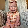 baby, child, smiling, blue_eyes, headband, bow, peach_pattern, onesie, sitting, plush_blanket, furniture, indoor, cute, happy, infant, skin, hands, feet, portrait, cozy
