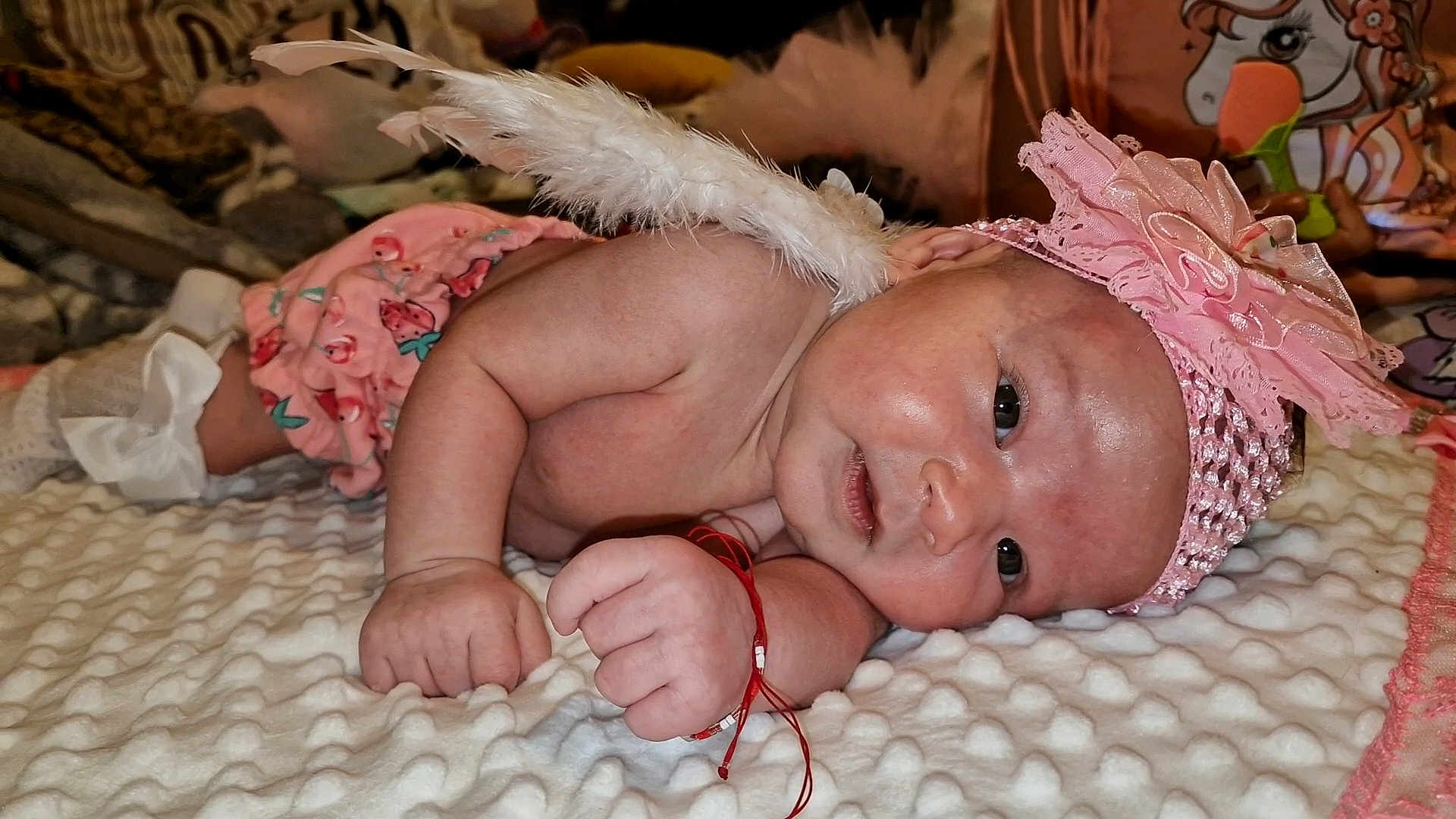 Selena participe au concours pour gagner de l'argent avec cette photo : baby, infant, angel, feather_wings, pink_headband, flower, blanket, cute, lying_down, soft_texture, skin, hand, face, expression, indoors, cozy, newborn, clothing, accessory, portrait