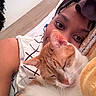 Daisy is registered to the contest to win money with this photo: person, cat, sleeping, close_up, indoor, bed, blanket, pillow, cozy, resting, snuggling, orange_cat, white_cat, portrait, relaxation, headwear, braids, earbuds, comfort, soft