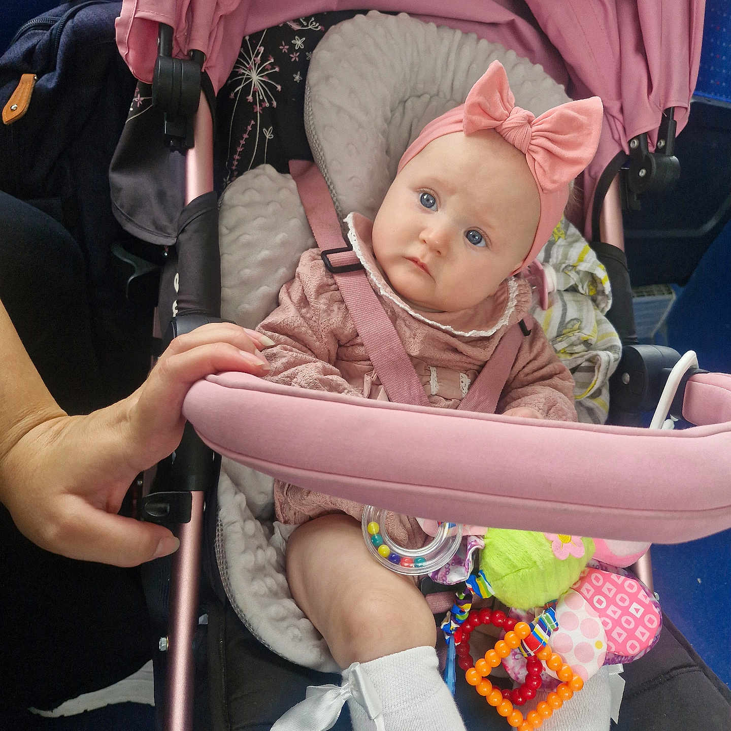 Lilah-Reign is registered to the contest to win money with this photo: baby, blue_eyes, bow, child, clothing, comfort, cute, expression, hand, headband, indoor, infant, person, pink, seatbelt, sitting, socks, soft_toys, stroller, toy