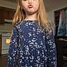 Bookie joined the competition — help win amazing prizes! blonde_hair, child, dress, duck_face, face, fashion, floral_dress, front_view, girl, home, indoors, kitchen, living_room, long_hair, person, photography, playful, portrait, pouting, standing