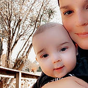 Colton joined the competition — help win amazing prizes! baby, child, person, adult, face, smile, outdoor, nature, tree, wooden_fence, arm, skin, closeup, holding, happy, daylight, portrait, family, love, casual_clothing