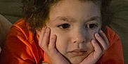 Cameron joined the competition — help win amazing prizes! bed, bedding, blanket, casual_clothing, child, close_up, comfortable, cozy, curly_hair, face, hands_on_face, indoor, orange_shirt, pensive, person, portrait, relaxed, resting, thinking, young_person