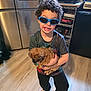 Cameron is registered to the contest to win money with this photo: appliance, boy, child, clothing, curly_hair, cute, dog, floor, holding, indoor, kitchen, oven, person, pet, playful, puppy, refrigerator, smiling, socks, sunglasses