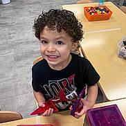 Cameron is registered to the contest to win money with this photo: blocks, boy, child, classroom, curly_hair, education, floor, happy, indoor, learning, person, plastic_shapes, play, preschool, purple_container, red_container, smiling, table, toys, wooden_chairs