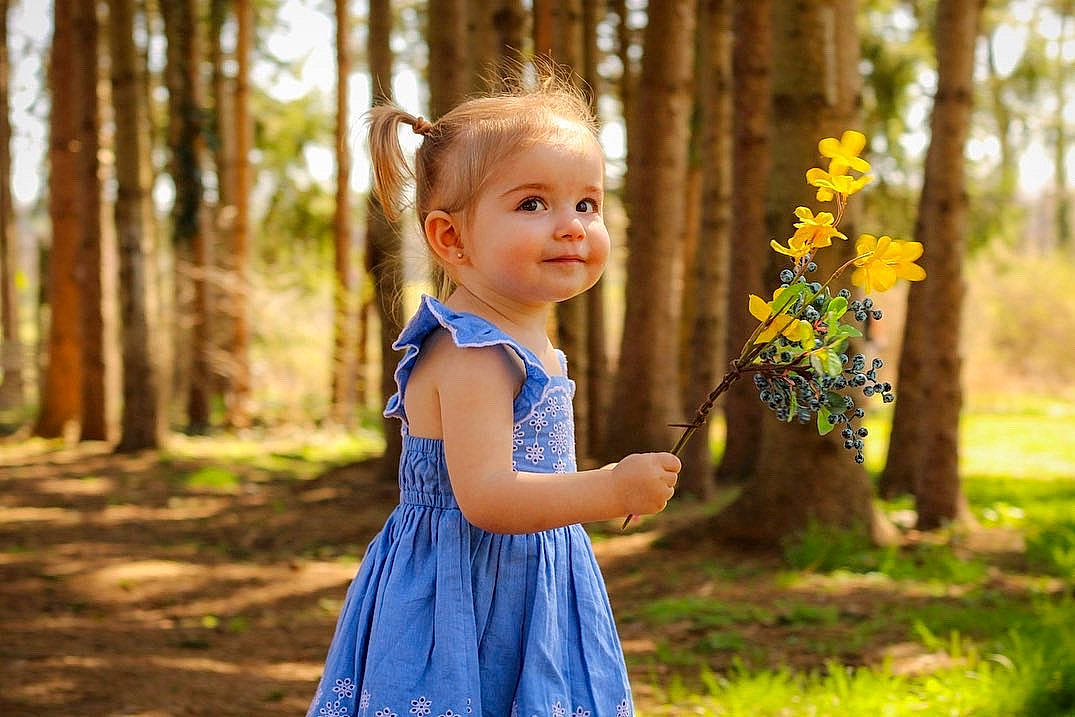 Hazel joined the competition — help win amazing prizes! baby_toddler_clothing, branch, child, dress, eye, flower, gesture, grass, happy, iris, leisure, people, people_in_nature, person, plant, standing, summer, sunlight, toddler, tree