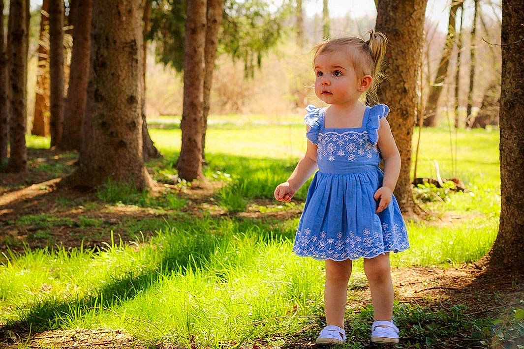 Hazel is registered to the contest to win money with this photo: baby_toddler_clothing, day_dress, electric_blue, forest, fun, grass, grassland, happy, leisure, meadow, natural_landscape, one_piece_garment, people_in_nature, person, plant, summer, sunlight, toddler, tree, wood