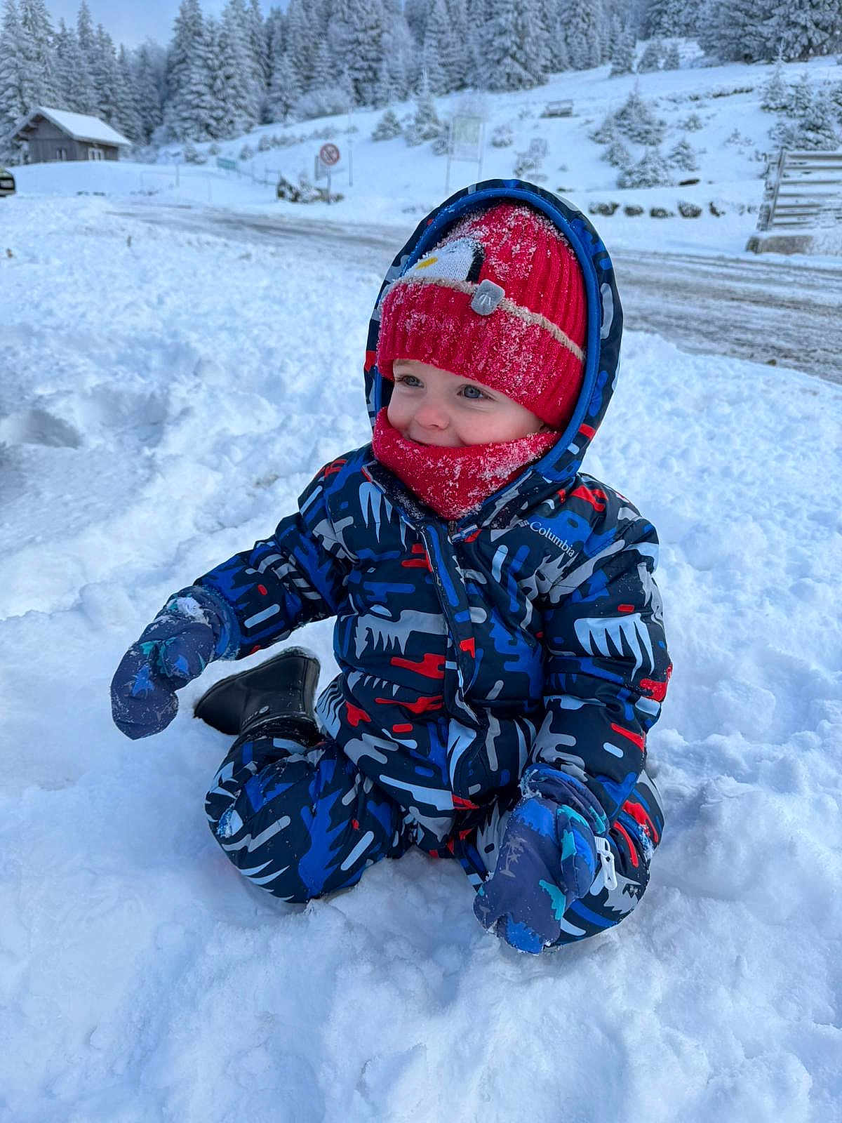 Elio participe au concours pour gagner de l'argent avec cette photo : child, toddler, snow, winter, outdoor, snowsuit, hat, mittens, cold, play, happy, blue, red, forest, cabin, nature, snowy, landscape, clothing, person
