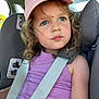 child, girl, car_seat, seatbelt, pink_cap, purple_tank_top, curly_hair, blue_eyes, car_interior, safety_strap, window, daylight, portrait, cute, young_person, expression, casual_clothing, closeup, seat, summer