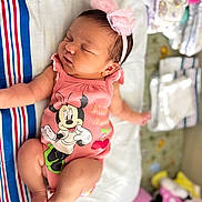 Kylie is registered to the contest to win money with this photo: baby, infant, sleeping, pink, headband, mickey_mouse, minnie_mouse, clothing, blanket, striped, bed, toys, nursery, cute, child, newborn, peaceful, soft, indoors, portrait