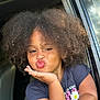child, curly_hair, afro, kiss, car_window, tshirt, smile, cute, playful, portrait, person, young_child, outdoor, happy, skin, face, hand, gesture, casual_clothing, daylight