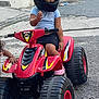 child, helmet, toy_vehicle, quad_bike, red, street, sidewalk, curious, outdoor, casual_clothing, shorts, pink_shoes, hand, asphalt, urban, daytime, play, helmet_visor, person, kid