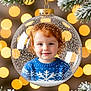 child, toddler, face, red_hair, blue_sweater, snowflake_pattern, christmas_ornament, glass_ball, holiday, festive, bokeh, lights, pine_branches, snow, winter, portrait, smile, cute, decoration, celebration
