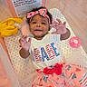 Akira is registered to the contest to win money with this photo: baby, child, infant, smiling, playpen, headband, outfit, dress, hands, warning_label, pink, red, white, blue, stars, hearts, toy, blanket, mesh, portrait