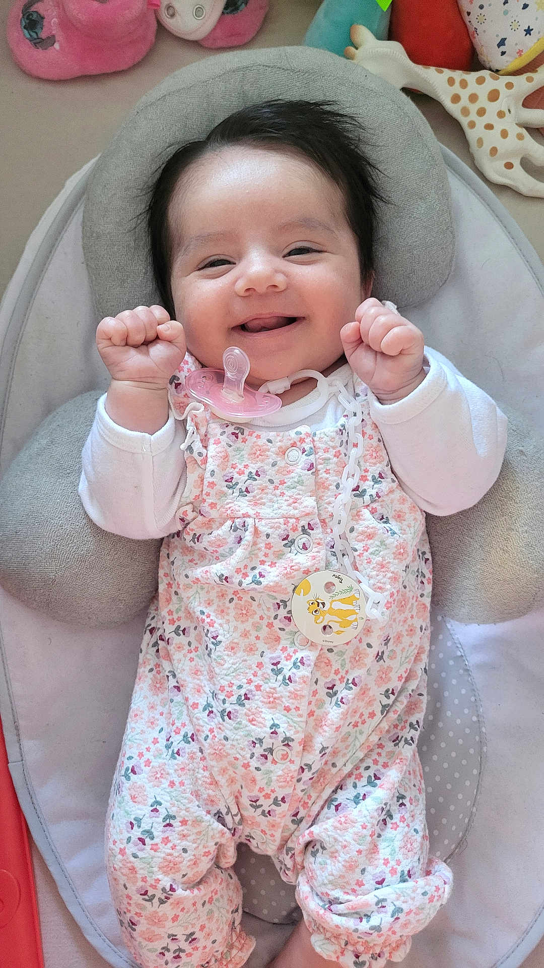 Amélia participe au concours pour gagner de l'argent avec cette photo : baby, smiling, pacifier, floral_clothing, baby_seat, cushion, toy, infant, happy, face, child, cute, indoors, comfort, lying_down, young_child, hands_up, soft_toys, patterned_clothing, closeup