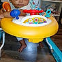 baby, walker, toy, floor, indoor, child, curious, person, foot, plastic, colorful, seat, play, furniture, cabinet, storage, room, electric_outlet, cable, wood_floor