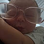 Atlas is registered to the contest to win money with this photo: baby, sleeping, glasses, close_up, face, infant, cute, peaceful, cozy, child, arm, white_clothing, patterned_clothing, indoor, portrait, head, eyewear, soft_light, resting, young