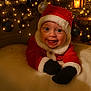 Atlas is registered to the contest to win money with this photo: baby, christmas, santa_hat, holiday_lights, ornaments, festive, smile, glowing_lights, red_clothing, black_mittens, christmas_tree, holiday_decor, cute, infant, celebration, warm_lighting, indoors, joyful, festivity, pinecones