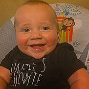 Ryan joined the competition — help win amazing prizes! baby, smiling, child, infant, face, happy, sitting, clothing, black_shirt, cheeks, eyes, baby_chair, monkey_illustration, balloons, indoor, cute, portrait, closeup, skin, person