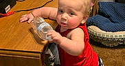 Ryan joined the competition — help win amazing prizes! toddler, child, red_tank_top, checkered_shorts, water_bottle, carpet, wooden_table, cables, indoor, curious, kneeling, furniture, plastic_container, pet_bed, blanket, household_items, baby, person, floor, room