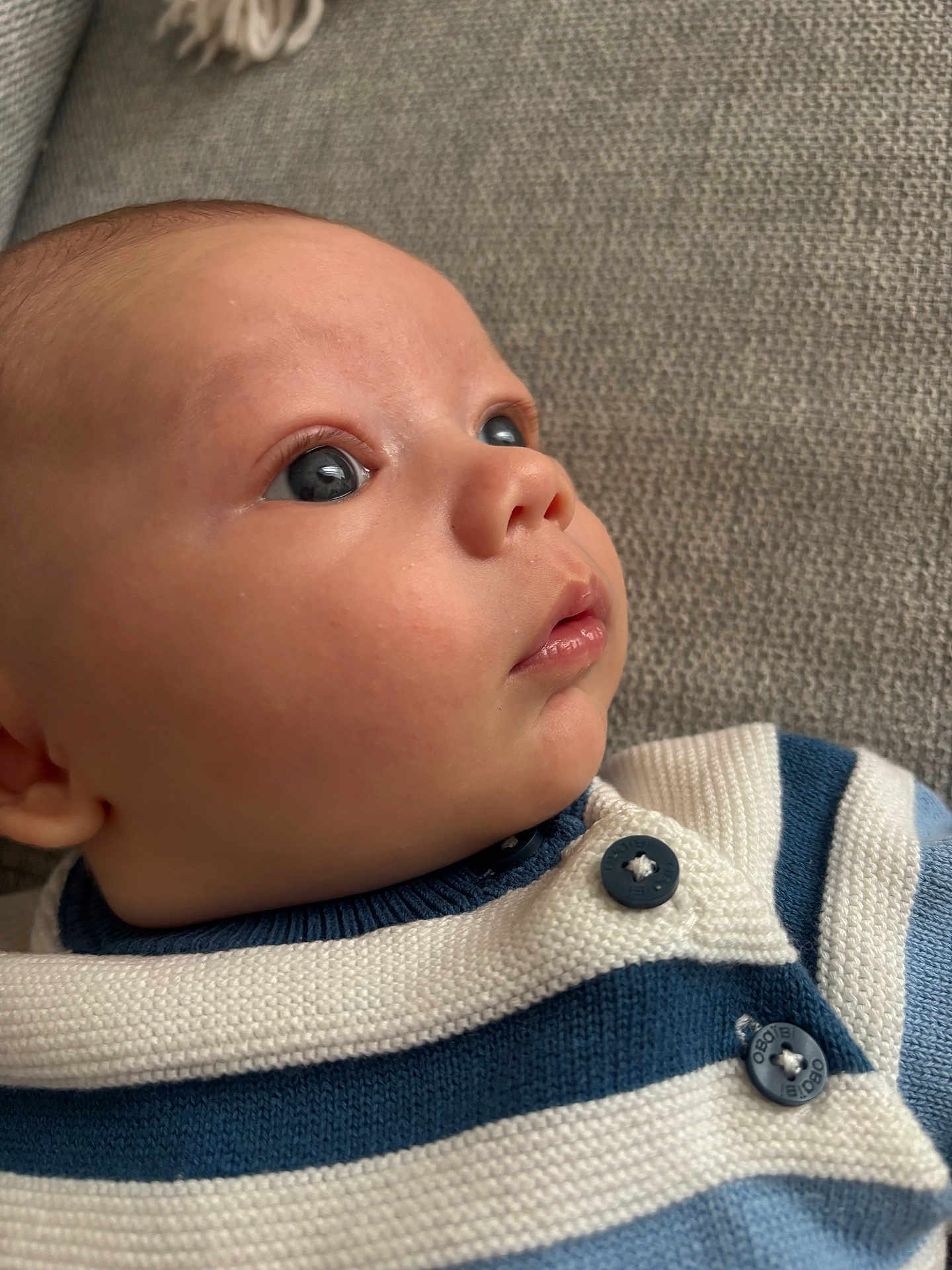 Liam participe au concours pour gagner de l'argent avec cette photo : baby, face, closeup, portrait, infant, blue_eyes, sweater, striped_clothing, button, texture, skin, child, young, cute, expression, looking_away, indoor, soft_light, fabric, cozy
