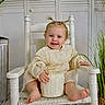 toddler, child, smiling, white_chair, cream_dress, cake, indoor, plant, wooden_floor, pigtails, happy, baby, portrait, seated, cute, decor, home, furniture, small_cake, person