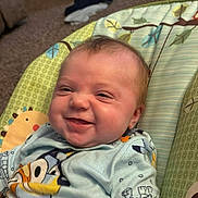 Violet is registered to the contest to win money with this photo: baby, smiling, infant, child, cute, clothing, cartoon_print, baby_seat, indoor, carpet, toy, folded_clothes, colorful, face, happy, person, seat_belt, pattern, relaxing, home