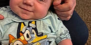 Violet is registered to the contest to win money with this photo: baby, child, infant, smiling, hand, tshirt, cartoon, indoor, carpet, couch, person, diaper, clip, holding, face, cute, closeup, seated, human, portrait